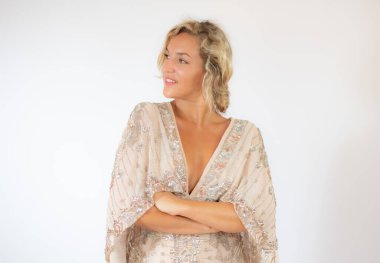 Beyaz arka planda, parti elbisesi içinde gülümseyen güzel sarışın kadın.