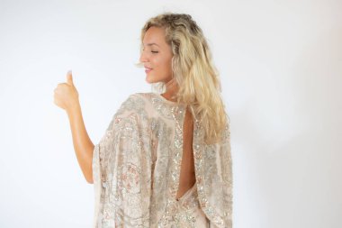 Beyaz arka planda, parti elbisesi içinde gülümseyen güzel sarışın kadın.