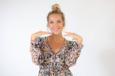 Beyaz arka planda beliren çiçekli elbiseli güzel sarışın kadın.