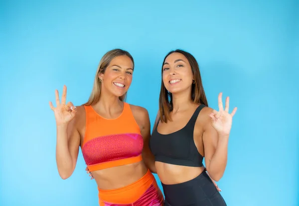 Two friends doing sport on blue background smiling