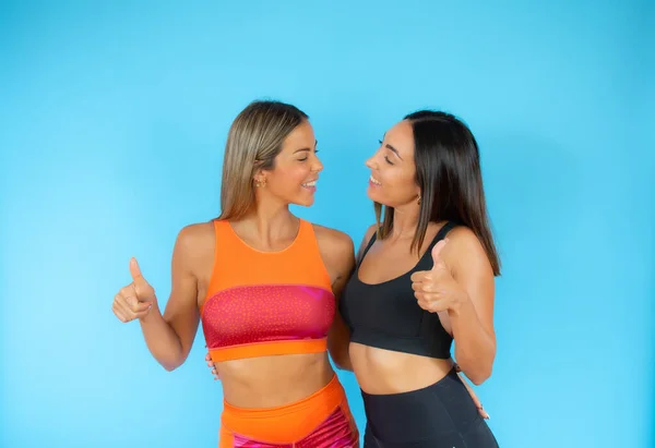 Two friends doing sport on blue background smiling