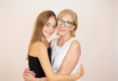 Gülümseyen yaşlı kadın beyaz arka planda torununa sarılıyor.