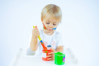 Yüzünde renkli boyalar olan, beyaz arka planda izole edilmiş hayret verici bir çocuk.