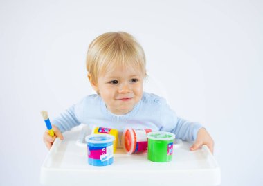 Yüzünde renkli boyalar olan, beyaz arka planda izole edilmiş hayret verici bir çocuk.