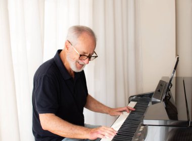 Yaşlı adam piyano çalıyor. Beyaz arkaplan karşısında izole