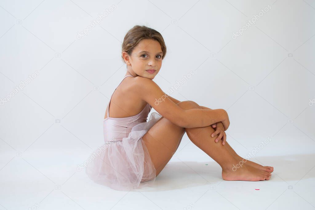 Beautiful little ballerina on floor doing stretching over white background