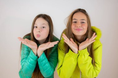 Beyaz arka planda kışlık ceketli iki gülen arkadaş.