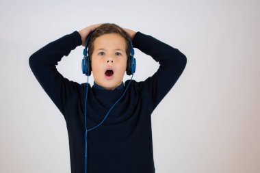 Kulaklık takmış, beyaz arka planda müzik dinleyen şirin bir çocuğun portresi. Mutlu çocuk..