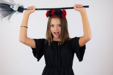 Siyah cadılar bayramı kostümü giymiş güzel bir kız resmi. Kameraya bakıyor ve beyaz arka planda izole bir şekilde gülümsüyor.