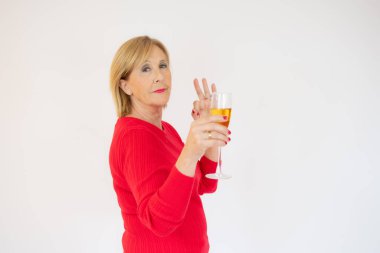 Beyaz arka planda şampanya içen mutlu kıdemli zarif kadın.