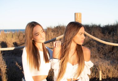 Gün batımında arka planda sıcak bir ışıkla parkta poz veren iki mutlu arkadaşın ön manzara portresi