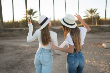 Güneşin doğuşunda, arka planda sıcak bir ışıkla parkta birlikte yürüyen iki arkadaşın arka planı.