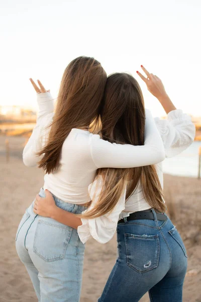 Kumsalda birbirini kucaklayan iki genç kız.