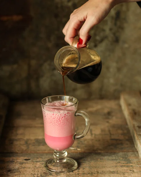 lattebeetroot (beet juice) - pink coffee with milk in a transparent cup on the table.