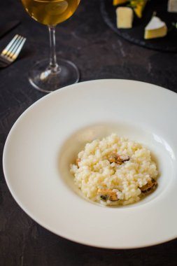 beyaz bir tabak ve bardak beyaz wineon karanlık bir arka plan risottowith midye (deniz ürünleri pirinç)