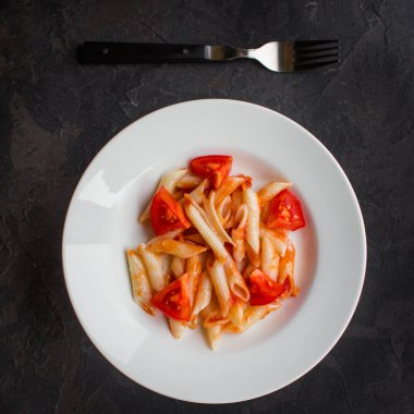 Makarna, penne, domates sosu ve domates. Vegan gıda. (koyu arka plan). üstten görünüm. kopya alanı