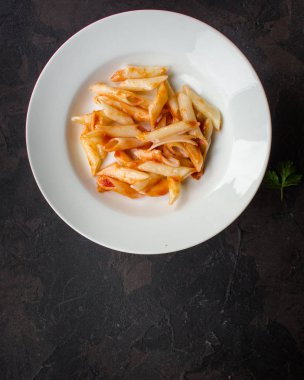 Makarna, penne, domates sosu ve domates. Vegan gıda. (koyu arka plan). üstten görünüm. kopya alanı