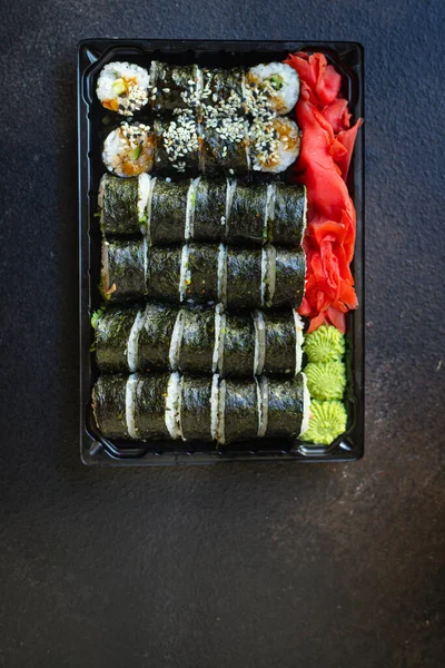 sushi rolls salmon fish flying fish roe vegetables ginger wasabi rice and nori on the table top view place copy space for text food background rustic