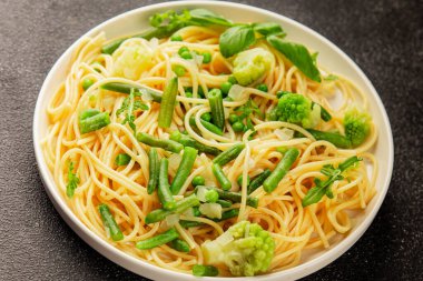 Spagetti sebzesi, bezelye, brokoli, çalı fasulyesi, kohlrabi vejetaryen makarna lezzetli makarna masanın üzerinde taze lezzetli gurme yemek.