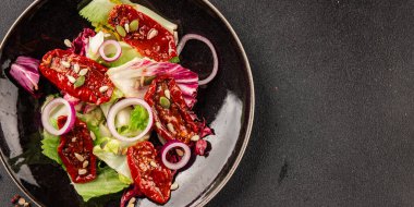 Salata, kurutulmuş domates, yeşil yaprak, soğan, doğal ürün, lezzetli aperatif. Lezzetli gurme yemek arkaplanı, masa, rustik üst manzara, fotokopi alanı, vejetaryen diyeti ve vejetaryen yemeği.