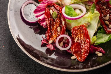 Salata, kurutulmuş domates, yeşil yaprak, soğan, doğal ürün, lezzetli aperatif. Lezzetli gurme yemek arkaplanı, masa, rustik üst manzara, fotokopi alanı, vejetaryen diyeti ve vejetaryen yemeği.