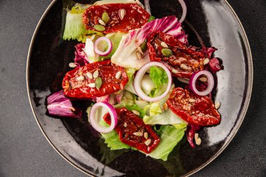 Salata, kurutulmuş domates, yeşil yaprak, soğan, doğal ürün, lezzetli aperatif. Lezzetli gurme yemek arkaplanı, masa, rustik üst manzara, fotokopi alanı, vejetaryen diyeti ve vejetaryen yemeği.