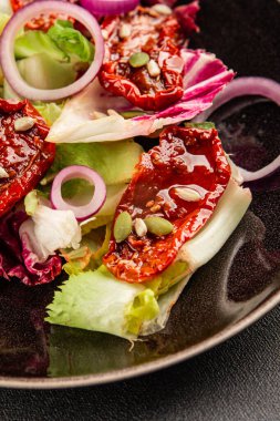Salata, kurutulmuş domates, yeşil yaprak, soğan, doğal ürün, lezzetli aperatif. Lezzetli gurme yemek arkaplanı, masa, rustik üst manzara, fotokopi alanı, vejetaryen diyeti ve vejetaryen yemeği.