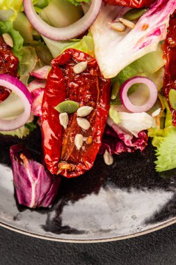 Salata, kurutulmuş domates, yeşil yaprak, soğan, doğal ürün, lezzetli aperatif. Lezzetli gurme yemek arkaplanı, masa, rustik üst manzara, fotokopi alanı, vejetaryen diyeti ve vejetaryen yemeği.