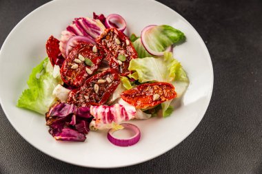 Salata, kurutulmuş domates, yeşil yaprak, soğan, doğal ürün, lezzetli aperatif. Lezzetli gurme yemek arkaplanı, masa, rustik üst manzara, fotokopi alanı, vejetaryen diyeti ve vejetaryen yemeği.