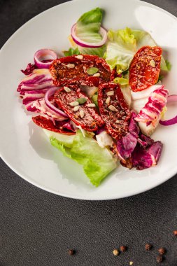 Salata, kurutulmuş domates, yeşil yaprak, soğan, doğal ürün, lezzetli aperatif. Lezzetli gurme yemek arkaplanı, masa, rustik üst manzara, fotokopi alanı, vejetaryen diyeti ve vejetaryen yemeği.