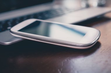 Ahşap masa üzerinde bir dizüstü eğik yansıması ile iş Smartphone