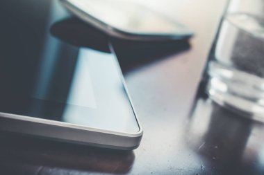İş Smartphone Tablet yanındaki bir Glas ahşap masa üzerinde yansıması ile eğilerek