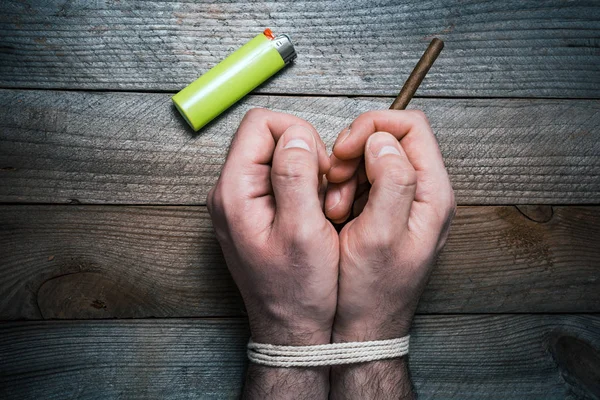 Deje de fumar concepto con 2 manos atadas en una mesa de madera junto a un encendedor. La mano derecha sostiene un cigarrillo —  Fotos de Stock