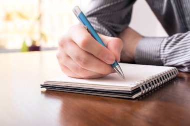 Bir erkekte iş gömleği yazılı bir Biro ile boş bir not defteri olarak önden görünümü