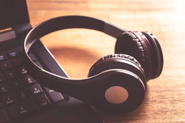 Bir dizüstü bilgisayar klavye üzerinde eğilerek küçük siyah kablosuz oyun kulaklığı