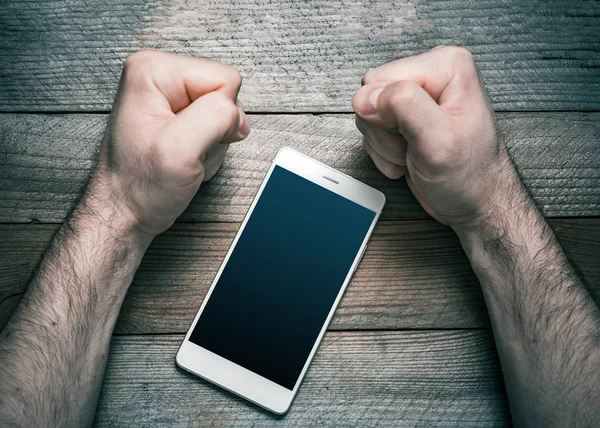 Κλείστε χρησιμοποιώντας Smartphone ή έννοια μέσα κοινωνικής δικτύωσης με ένα λευκό κινητό τηλέφωνο περιβάλλεται από 2 τόνισε αναζητούν σφιγμένες γροθιές — Φωτογραφία Αρχείου