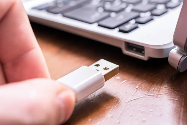 Männliche Hand, die ein weißes USB-Kabel mit dem USB-Port einer kleinen Tastatur verbindet — Stockfoto