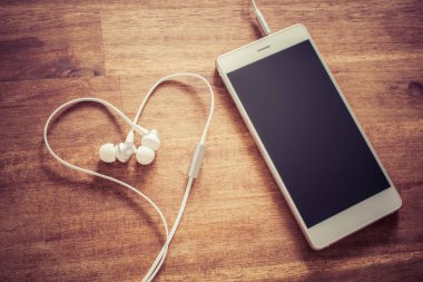 Kulaklýklý mikrofon seti bir aşk dinleme müzik konsepti ile beyaz cep telefonu ve bir kalp şeklinde