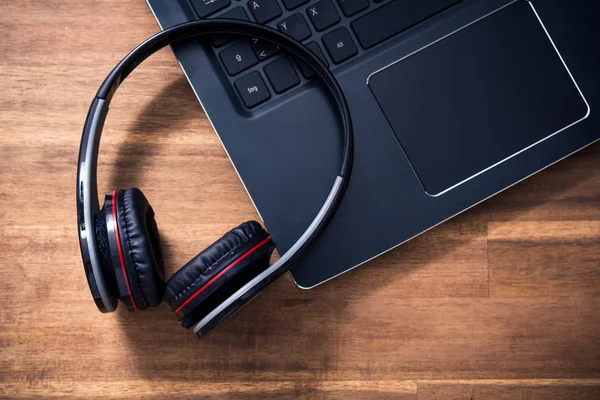 Zwarte draadloze Overhead Headset liggen op de hoek van een Notebook toetsenbord In een kantoor — Stockfoto