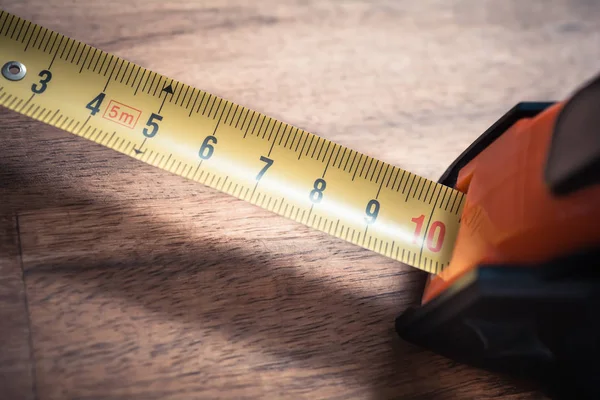 Una macro de una cinta métrica sólida con escala extraída de pie sobre una mesa — Foto de Stock