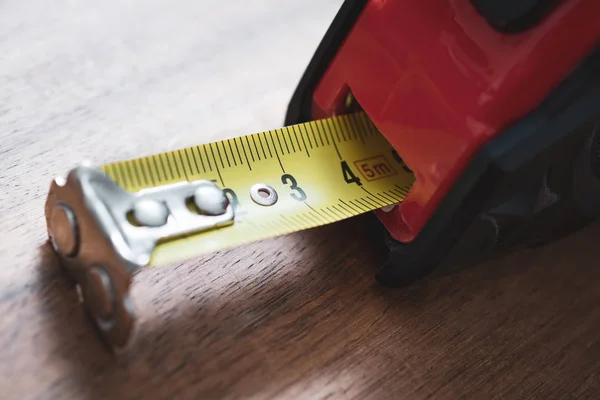 Um close-up de uma fita de medição sólida com escala puxada para fora de pé em uma mesa — Fotografia de Stock