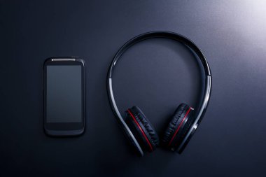 Sonraki yansıması ile koyu arka plan üzerinde siyah bir genel gider kulaklık yalan siyah cep telefonu