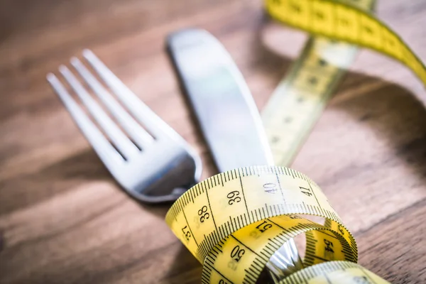 Macro de garfo e talheres amarrados com fita métrica em uma mesa - Perder peso conceito — Fotografia de Stock