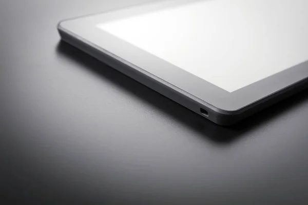 Tablet preto com reflexão deitado em um fundo escuro — Fotografia de Stock