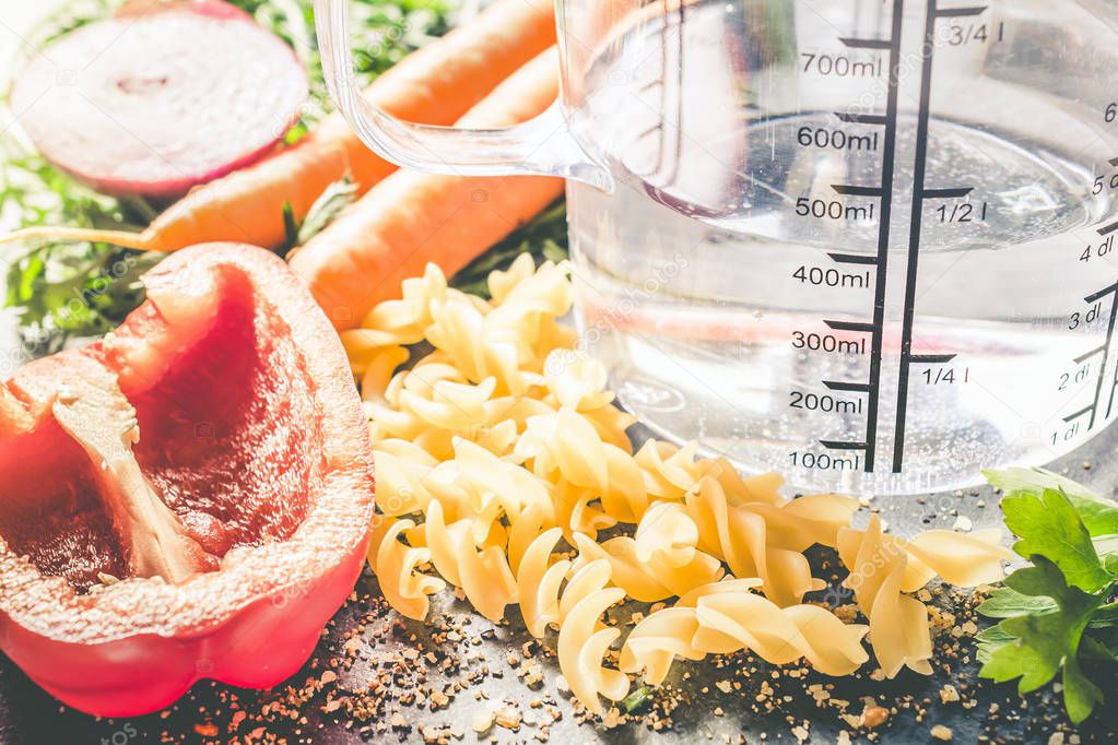 400 ml - ccm Water In A Measuring Cup Surrounded By Noodles, Pepper, Onion, Carrots And Spices