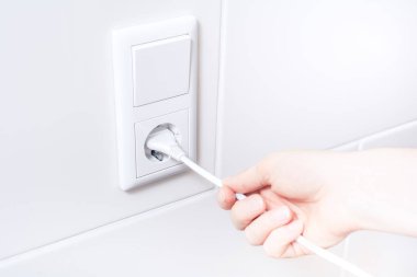 Enerji tasarrufu için duvar yuvasından bir elektrik kablosu çekerek