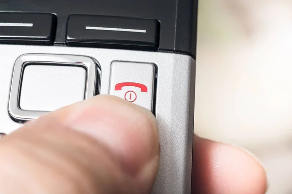 Mannelijke vinger op de rode ophangen knop van een draadloze Dect-telefoon, klaar om het gesprek te beëindigen Rechtenvrije Stockfoto's