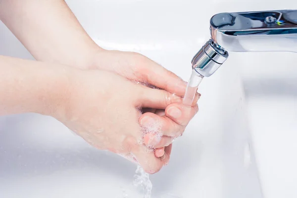 Vrouwelijke Soaped handenwassen onder aangezet Water In de badkamer Stockfoto