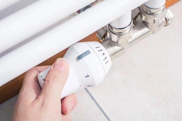 Homme main tourne le radiateur d'un chauffage de salle de bains blanche, concept d'économie d'énergie — Photo