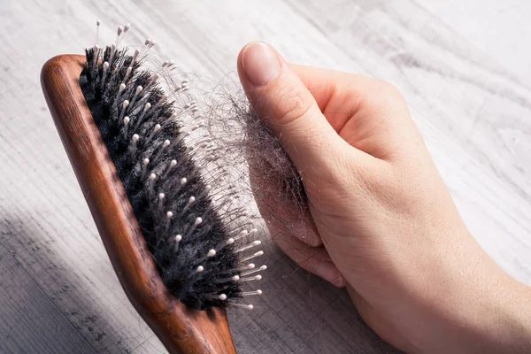 Kvinnlig Hand dra massa hår ur Brush - alopeci hår förlust koncept Royaltyfria Stockbilder